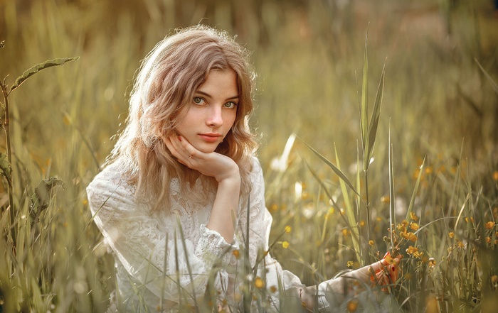 Blonde woman sitting in a field of grass