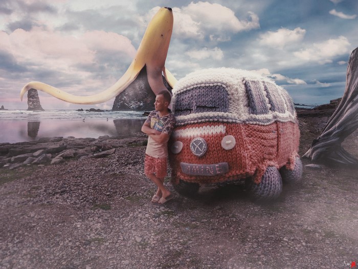 Man leaning on knitted van with giant banana on beach