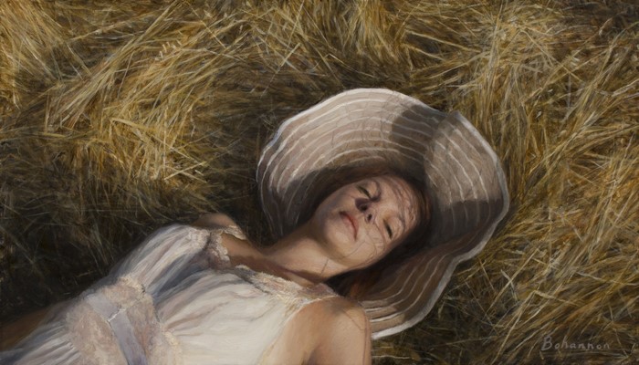 Woman in a straw hat lying in hay