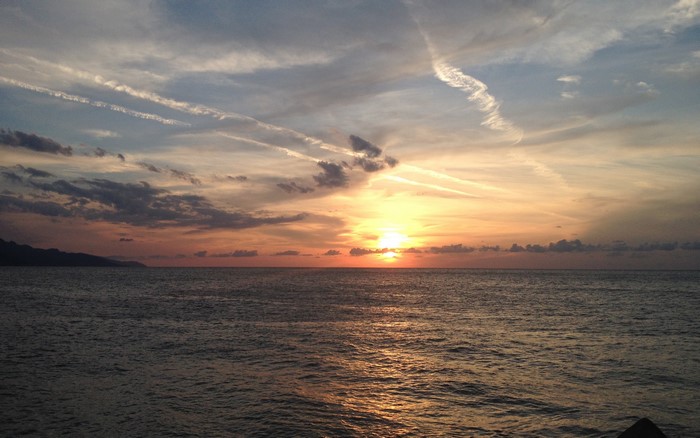 Sunset over the ocean with chemtrails