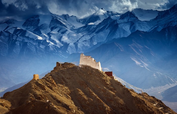 Ancient fortress on a mountain peak with snowy mountains in the background