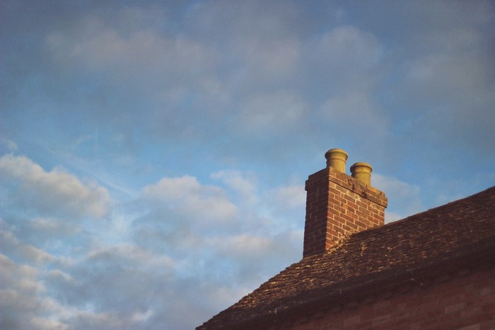 Brick chimney on a tiled roof against a cloudy sky