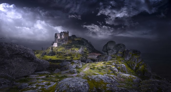 Castle ruin on a rocky hill under a dark sky