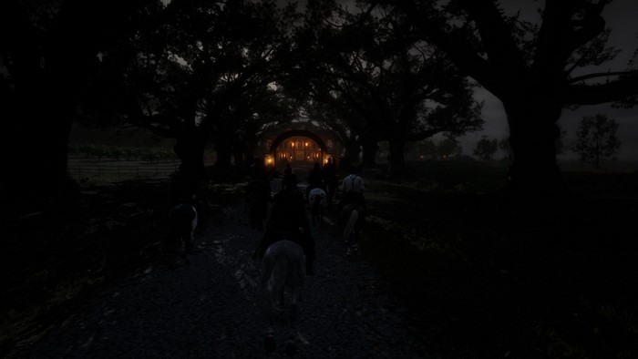 People on horseback approaching a building at night