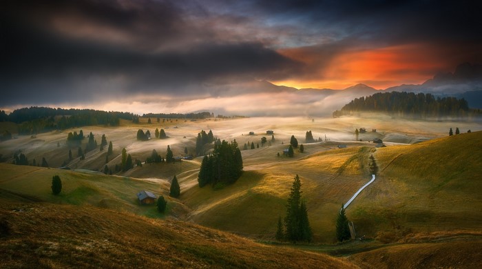 Misty mountain landscape at sunset with huts and trees