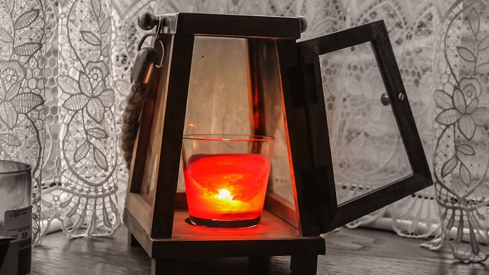 Lantern with a red candle and lace curtains