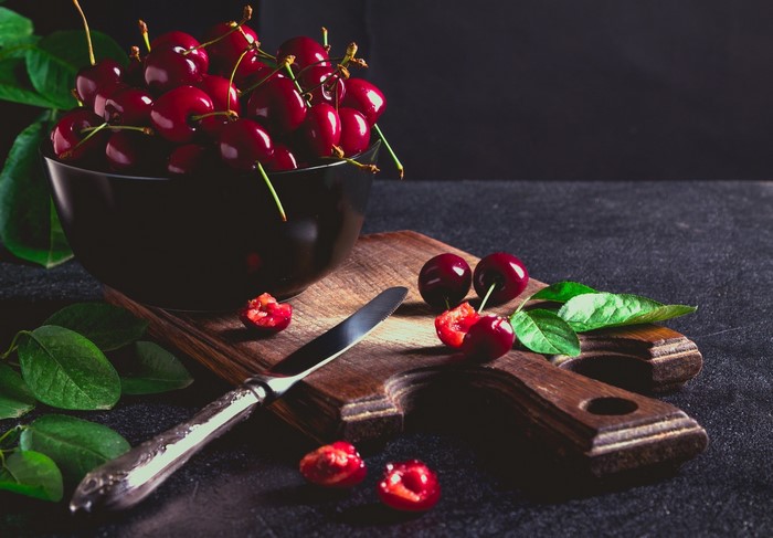 Cherries in a bowl with a knife on a cutting board