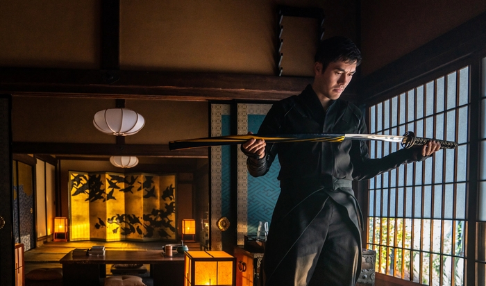 Henry Golding as Snake Eyes holding a sword