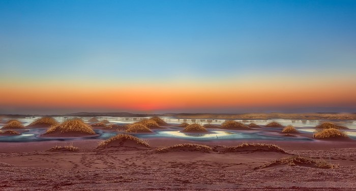 Desert landscape with mounds and sunset sky