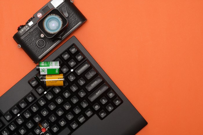 Leica M6 camera and film rolls on a keyboard