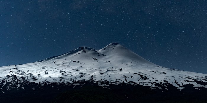Snow-covered mountain peak under a starry night sky