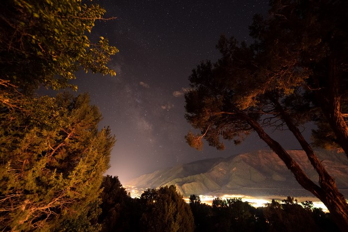 Night landscape with Milky Way over mountains and city lights
