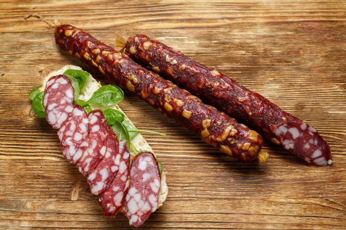 Two sausages and a sandwich with salami slices