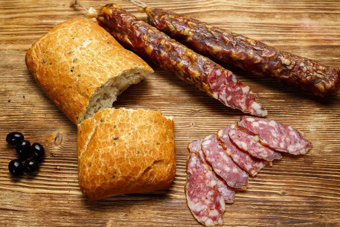 Bread, sausages, and olives on a wooden table