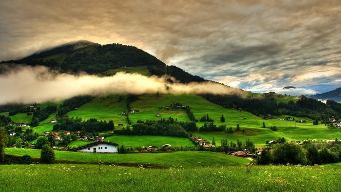 Green rolling hills with clouds over mountains