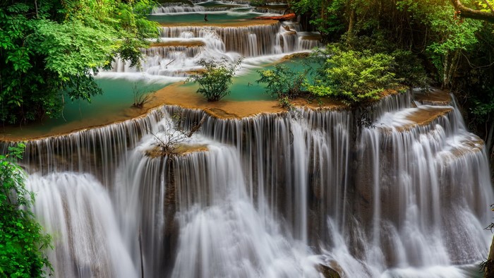 Tiered waterfall cascading through a lush green forest
