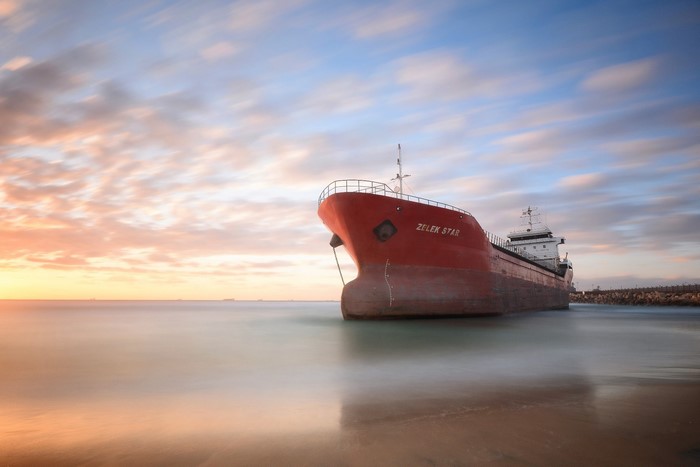 Red shipwreck on a beach at sunset