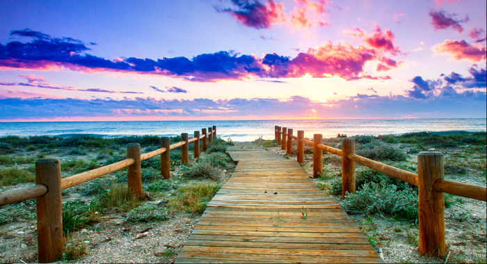 Wooden boardwalk to the ocean at sunset