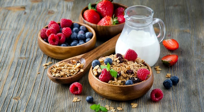 Granola with berries and milk in wooden bowls