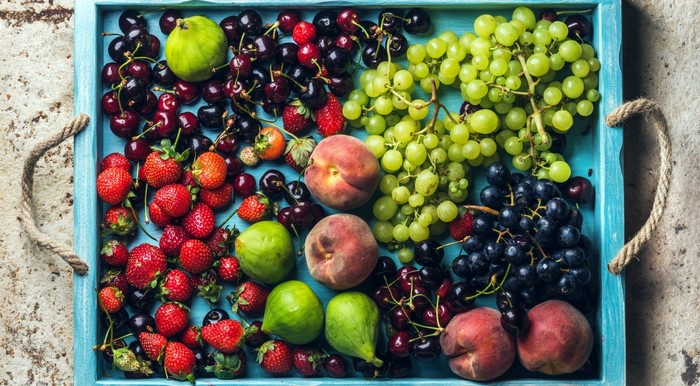 Colorful fruit platter with grapes, berries, peaches, and figs