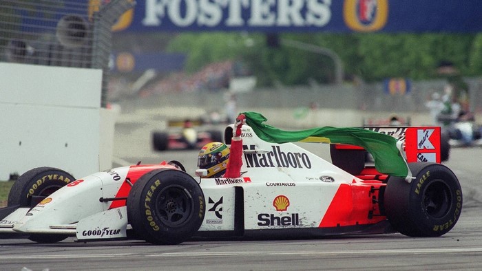 Ayrton Senna driving a McLaren Formula 1 car with a Brazilian flag