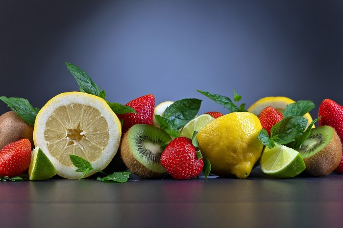Assortment of fresh fruits including strawberries, lemons, kiwi, and lime