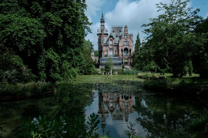 Castle reflected in a pond surrounded by trees