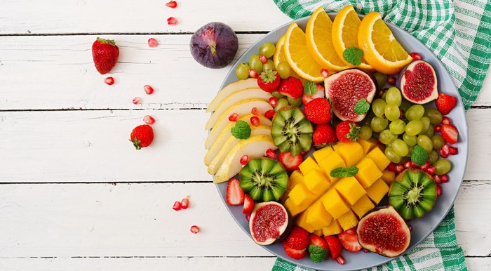 Colorful fruit platter with strawberries, mango, grapes, figs, oranges, kiwi, and pears