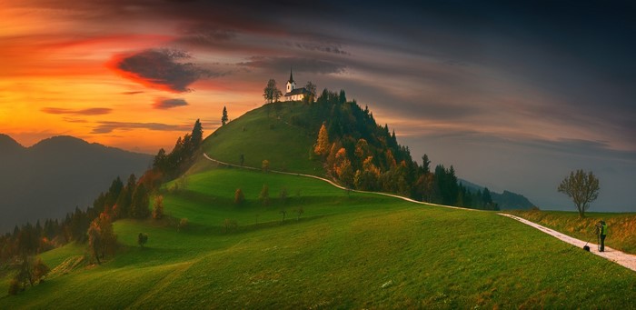Church on a hill at sunset with a person and dog