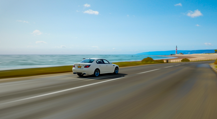 White BMW M5 driving on a coastal road in Forza Horizon 4