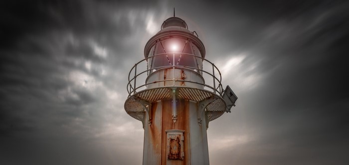 Rusted lighthouse against a stormy sky