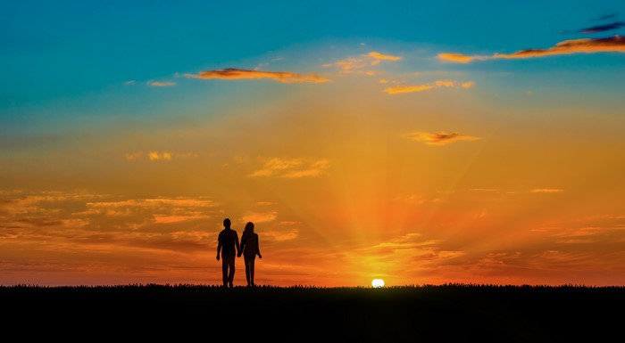 Couple walking at sunset silhouette