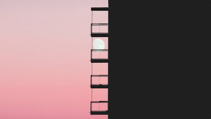 Balconies on a building with the moon in the sky