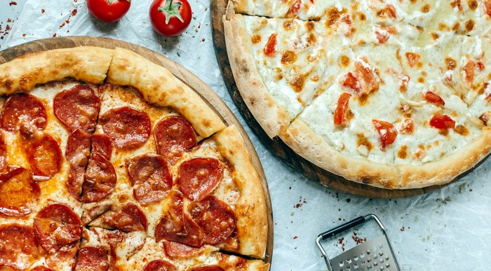 Two pizzas with pepperoni and tomatoes and cheese