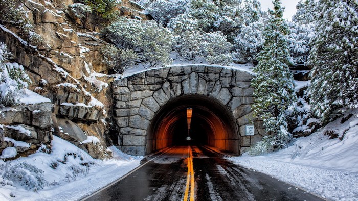 Snowy mountain tunnel entrance with road