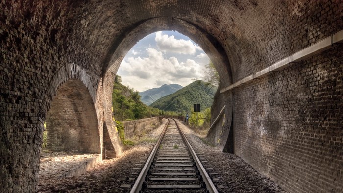 Train tunnel opening to mountains and railway