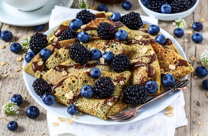 Pancakes with blackberries and blueberries drizzled with chocolate