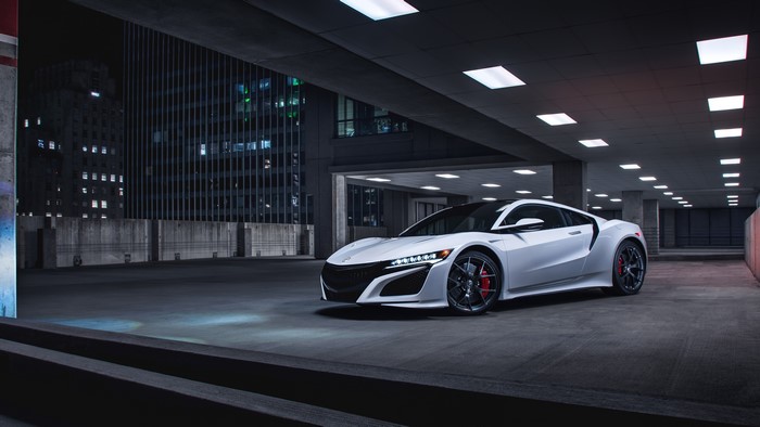 White Acura NSX sports car in parking garage at night
