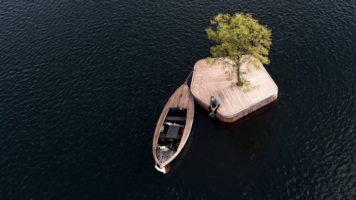 Wooden boat tied to a floating island with a tree