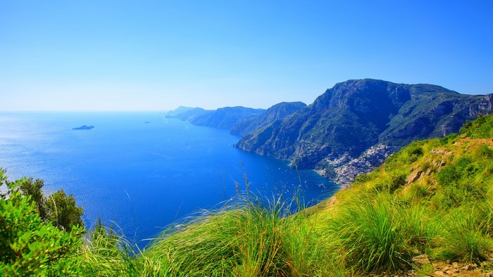 Coastal mountains and sea with green grass in foreground