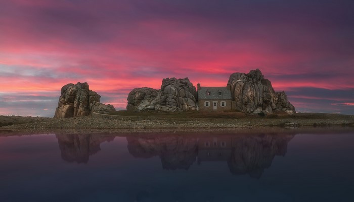 House on rocks with sunset reflection