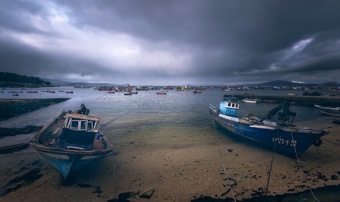 Fishing boats moored in a harbor under a cloudy sky