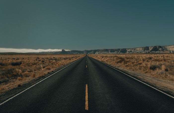 Asphalt road through a desert landscape with mountains