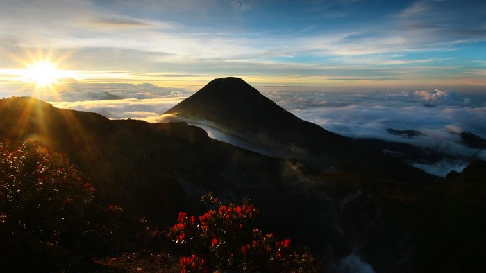 Sunrise over mountains with sun rays and clouds