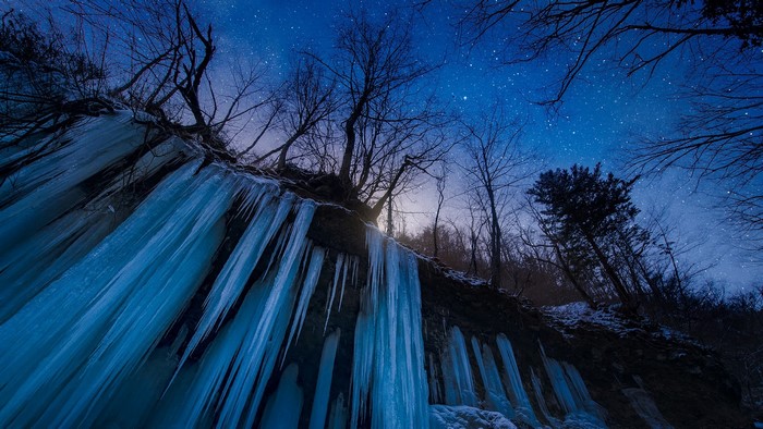 Frozen waterfall under a starry night sky