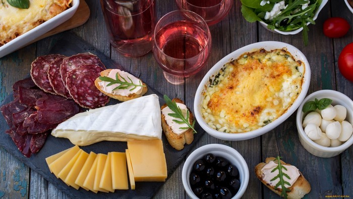 Charcuterie board with cheese, sausage, olives, and wine