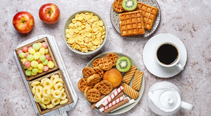 Breakfast spread with waffles, cereal, fruit, cookies, and coffee