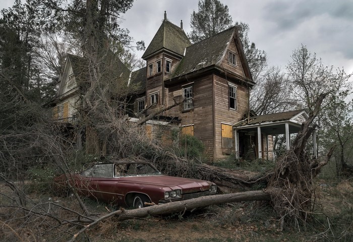 Abandoned house with a car and fallen trees