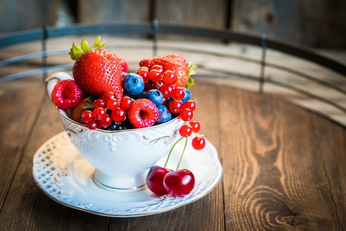 Cup of mixed berries and cherries on a wooden surface