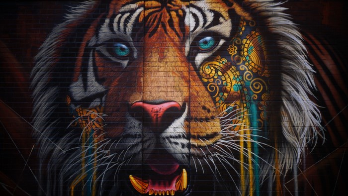 Graffiti of a colorful tiger face on a brick wall